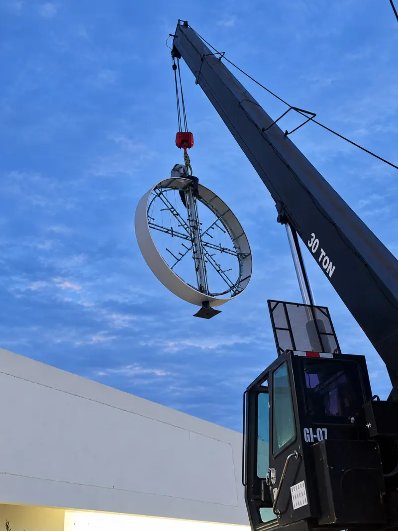 Tótem con aro circular en lo alto, grúa Titán a un lado y líneas aéreas sobre el área de trabajo.