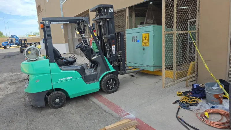 Montacargas transportado en una plataforma, seguido por una camioneta y el camión con grúa.